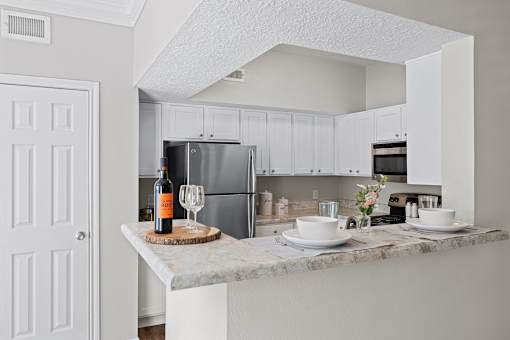 A kitchen with a marble countertop and white cabinets.