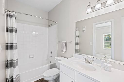 A white bathroom with a toilet, sink, and shower.