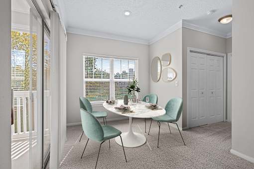 A dining room with a white table and green chairs.