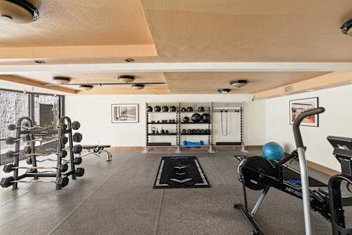 A gym with a variety of equipment including weights and a rowing machine.