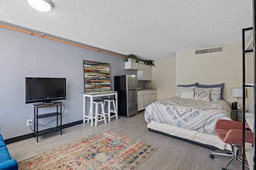 A bedroom with a bed, a chair, and a television.