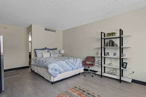 A bedroom with a bed, chair, and shelves.