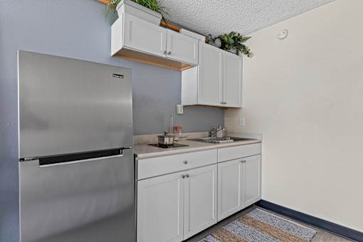 A kitchen with a stainless steel refrigerator and white cabinets.