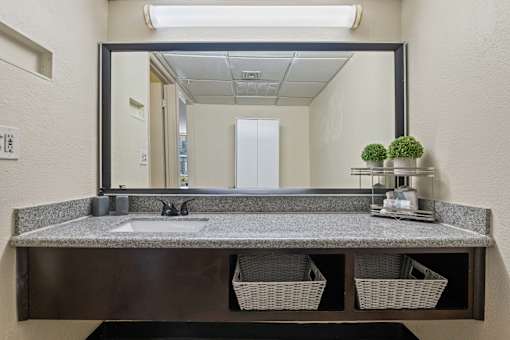 A bathroom vanity with a mirror, sink, and baskets.