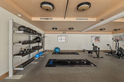 A gym with a variety of equipment including weights, a balance ball, and a stationary bike.