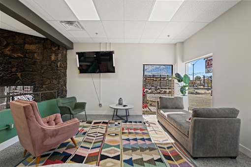 A living room with a stone wall and a flat screen TV mounted on the wall.