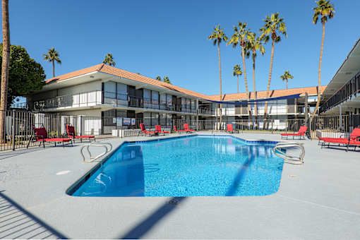 A swimming pool in front of a building with palm trees.
