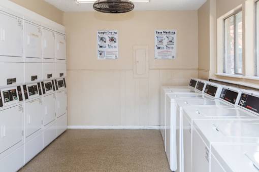 A laundry room with a row of washers and dryers.