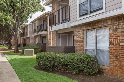 A row of apartment buildings with green bushes in front.