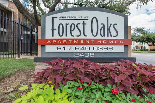 A sign for Westmont at Forest Oaks Apartment Homes with a phone number on it.