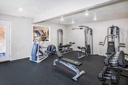 A spacious home gym with a variety of equipment including a treadmill, weights, and a bench press.