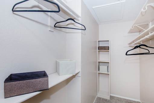 A white closet with a shelf and a purple storage bin.