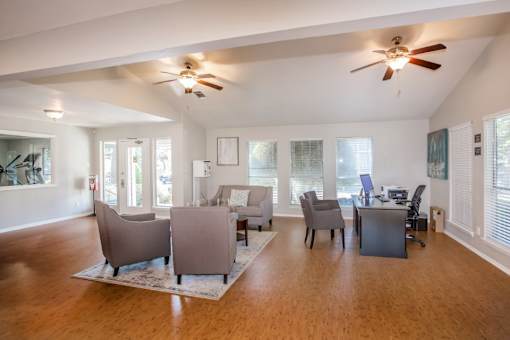 A spacious living room with a ceiling fan and a desk with a computer.