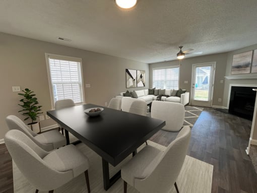a living room and dining room with white chairs and a black table