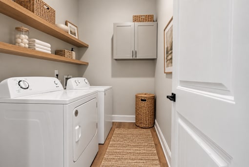 A laundry room with a washer and dryer, a basket, and a cabinet.