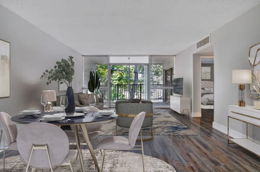 a living room with a dining room table and chairs and a balcony