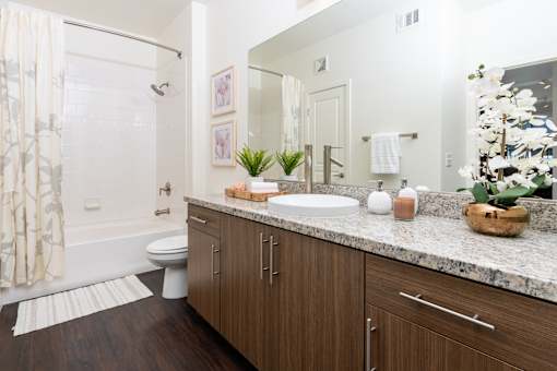 A bathroom with a white tub, sink, and wooden cabinets.
