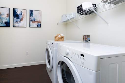 A white washing machine in a laundry room with a shelf above it.