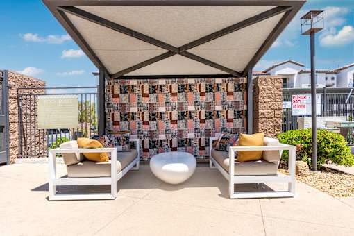 A patio with two chairs and a table under a canopy.