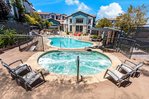A pool surrounded by chairs and a fence.