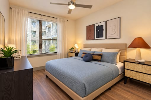 A bedroom with a bed, nightstand, and a ceiling fan.