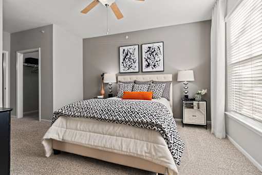 A bedroom with a bed, nightstand, and two framed pictures on the wall.