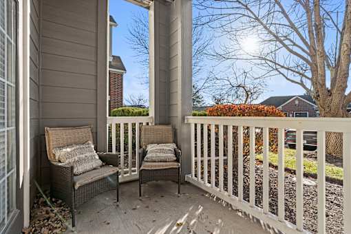 A patio with two chairs and a bench.