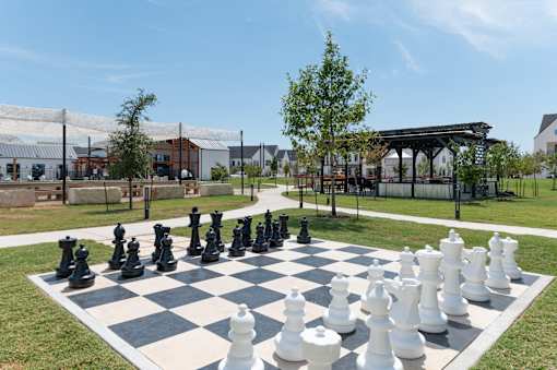 A giant chess set is set up on a grassy area.
