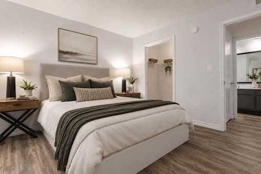 A bedroom with a large bed and a painting on the wall.
