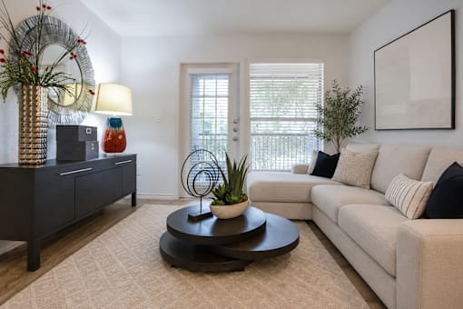 A living room with a white couch, a coffee table, and a side table with a lamp and a vase.