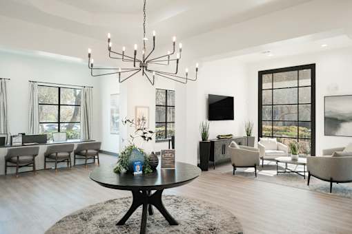 A modern living room with a black chandelier and a round table with a vase of flowers on it.