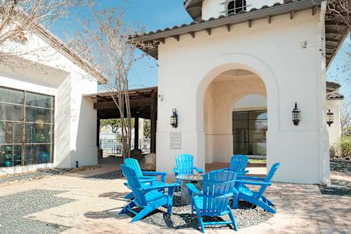 A white building with a blue table and chairs in front.