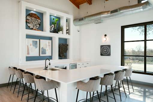 A kitchen with a long white island and chairs.