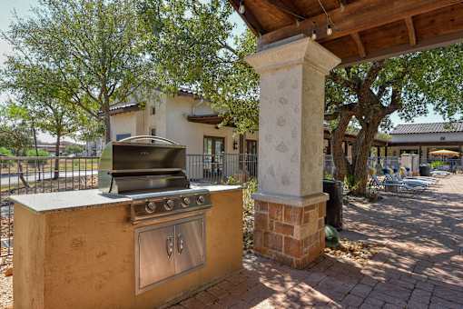A brick pillar stands next to a stove in a sunny outdoor area.