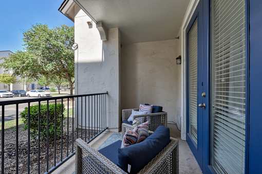 A balcony with a blue cushion and a black railing.