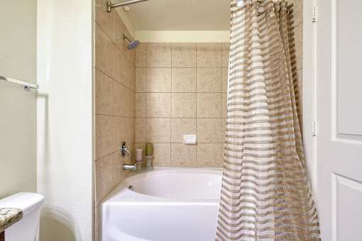 A bathroom with a white tub and a shower curtain.