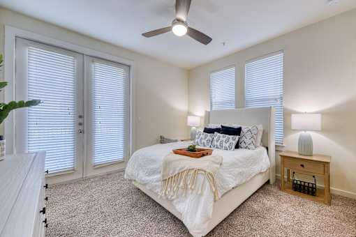A bedroom with a bed, a ceiling fan, and a nightstand.