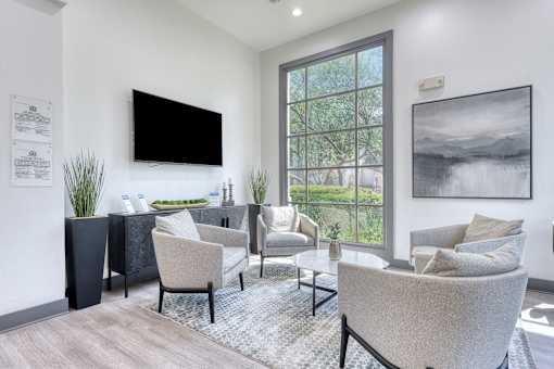 A living room with a large window, a flat screen TV, and a grey sofa.