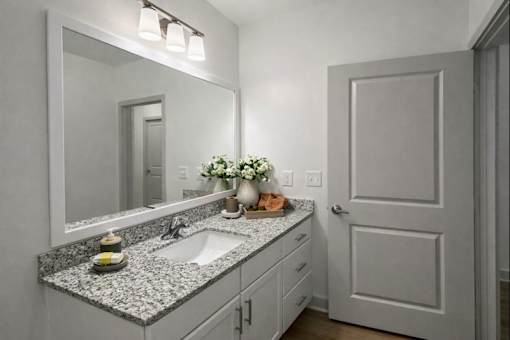 A bathroom with a sink, mirror, and a vase of flowers.