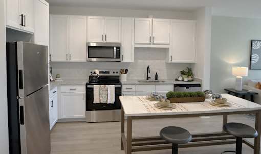 A modern kitchen with a refrigerator, microwave, oven, and sink.