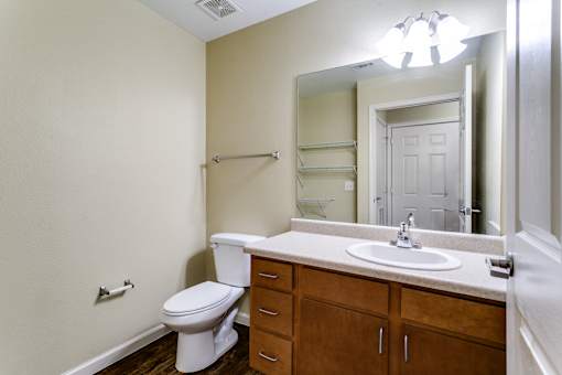 A bathroom with a toilet, sink, and mirror.