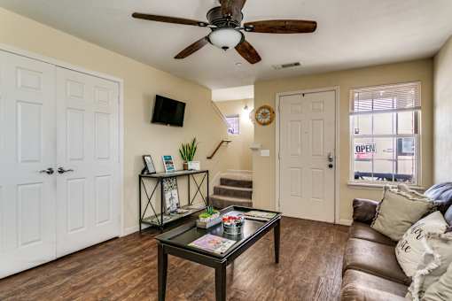 A living room with a brown leather couch and a ceiling fan.