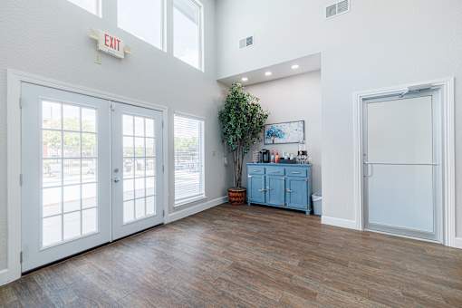 A room with a white wall and a wooden floor with a blue cabinet and a plant.