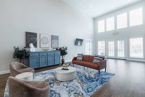 A living room with a blue rug and a brown sofa.
