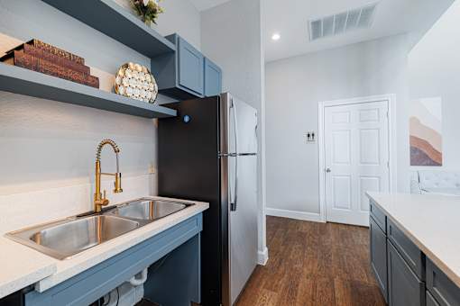 A kitchen with a black refrigerator and a white sink.