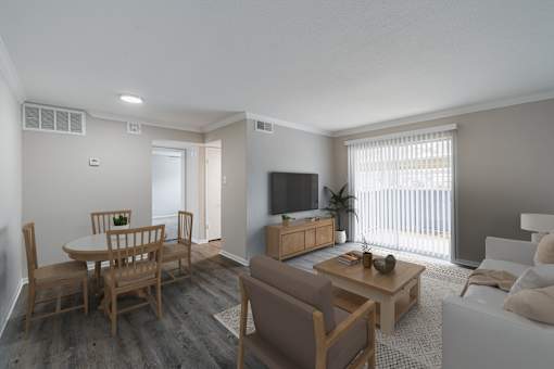 A living room with a white couch, a wooden dining table, and a television.