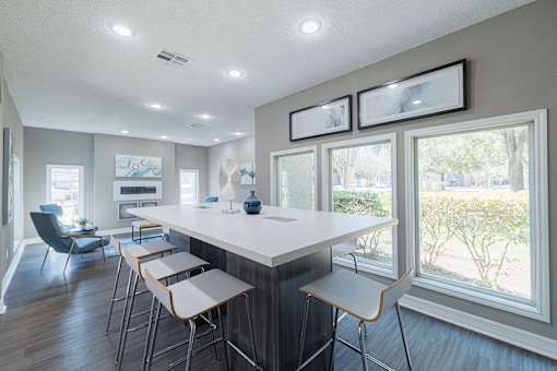 A modern kitchen with a long white island and bar stools.