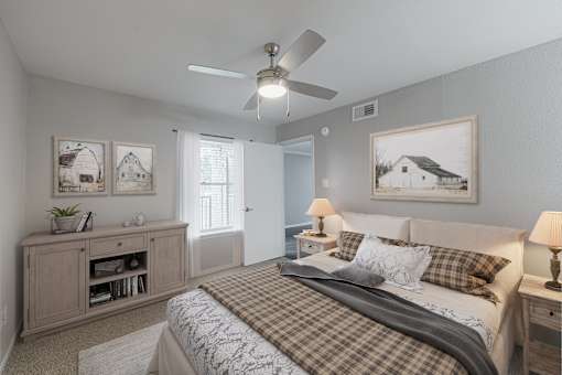 A bedroom with a bed, nightstand, and a cabinet with a plant on top.