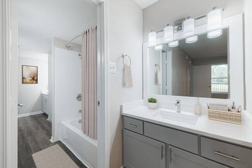 A bathroom with a sink, mirror, and shower.