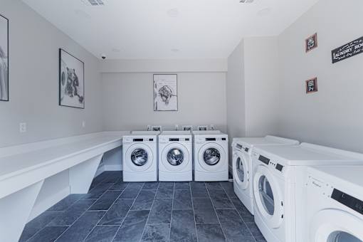 A laundry room with a row of washing machines.